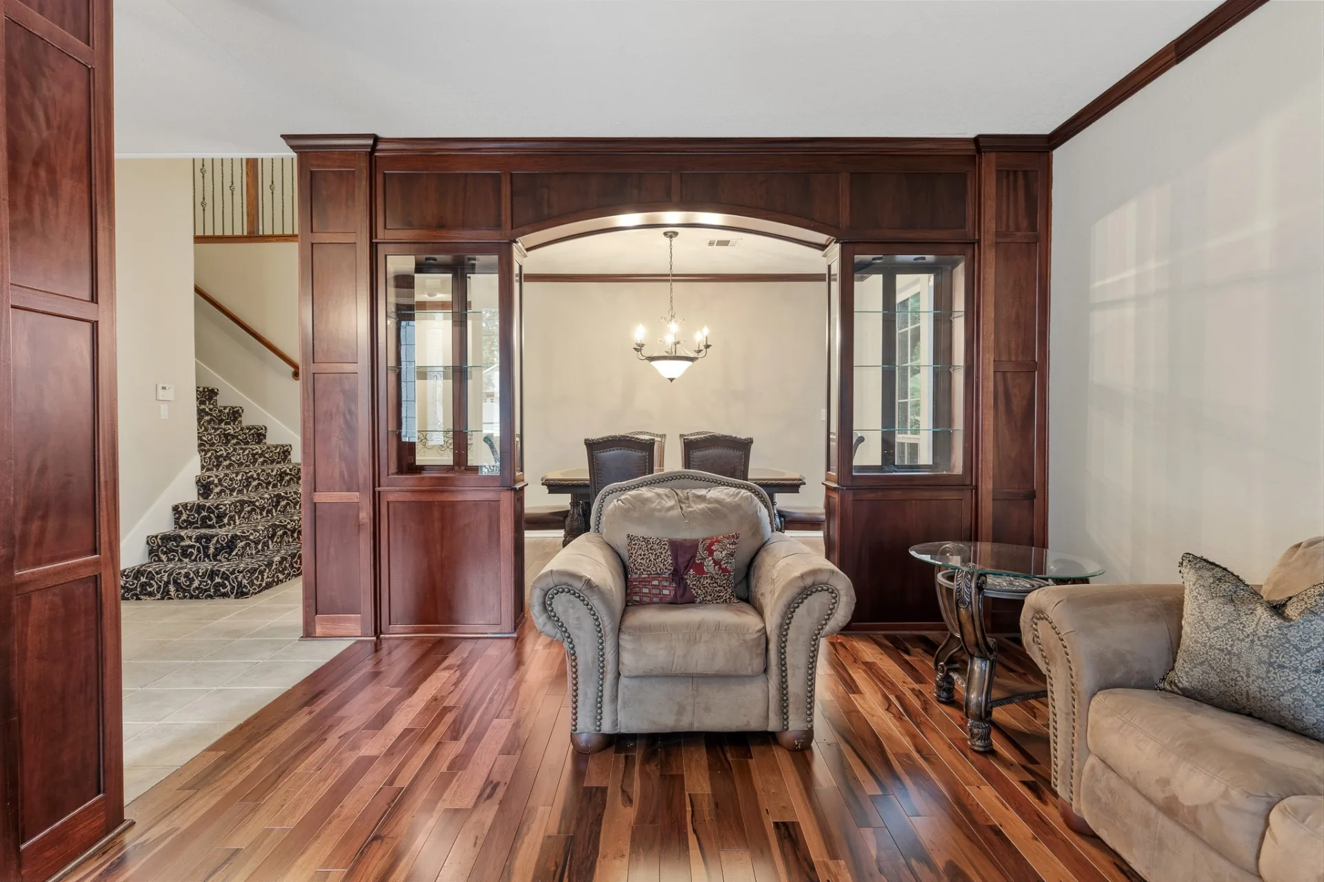 Living room view through arched cherry built-ins to dining room