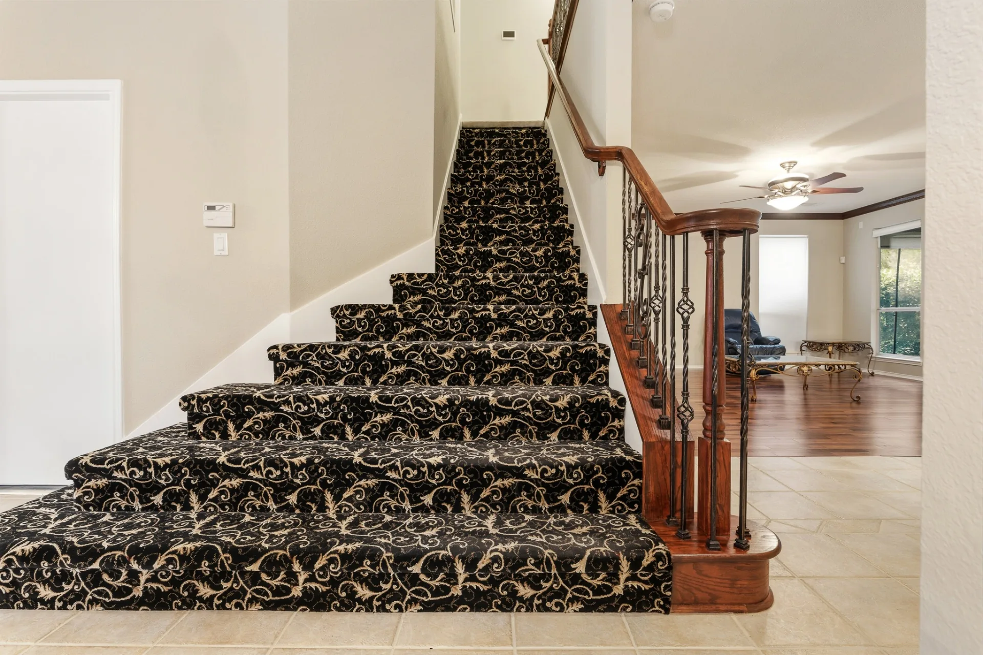 Curved staircase with patterned runner and wrought iron balusters