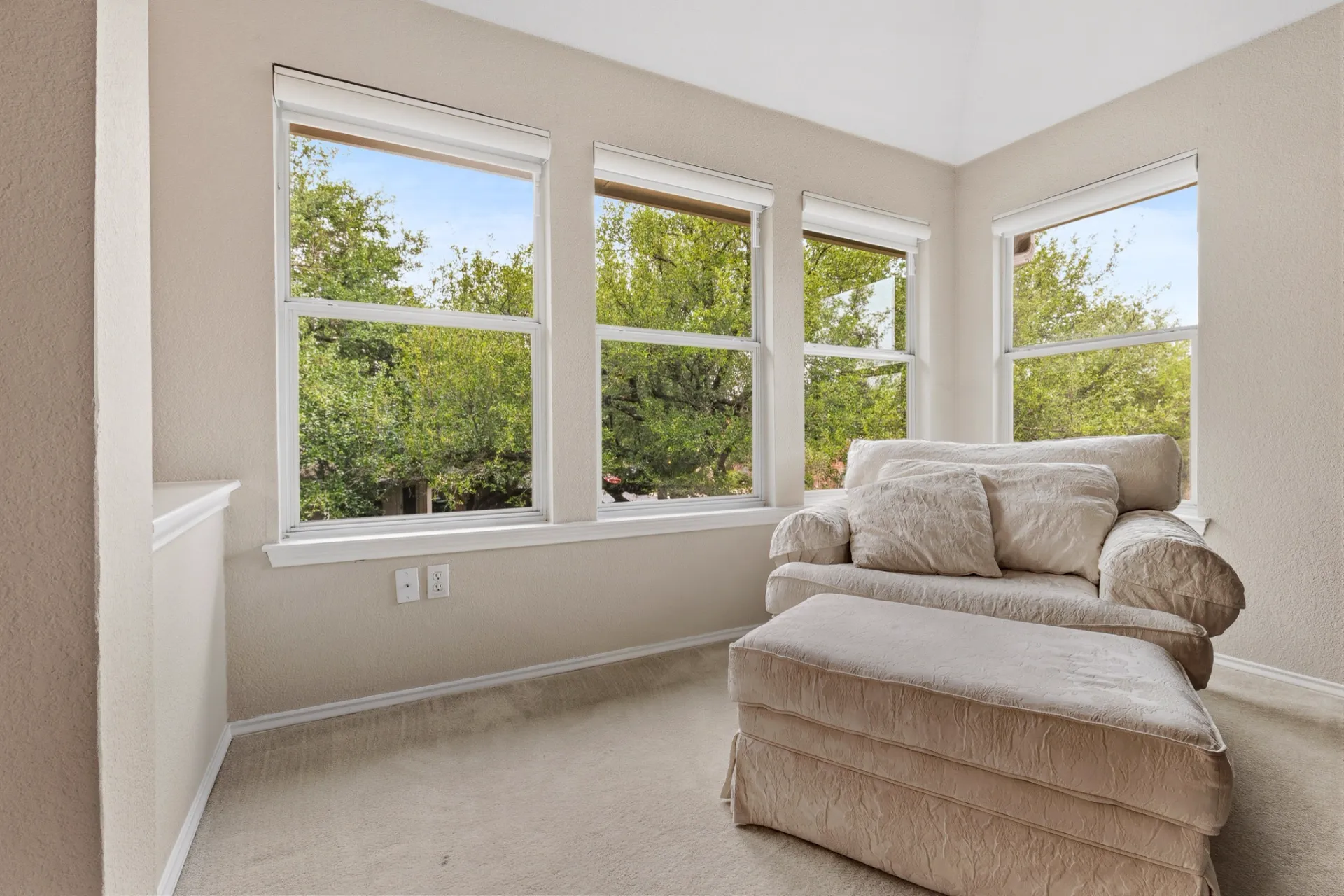 Primary bedroom sitting nook with wall of windows and treetop views